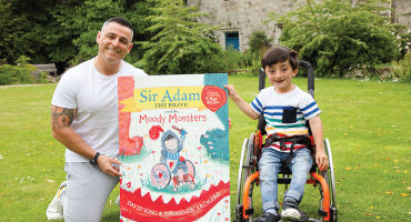 image of david and adam king holding a large poster in a garden